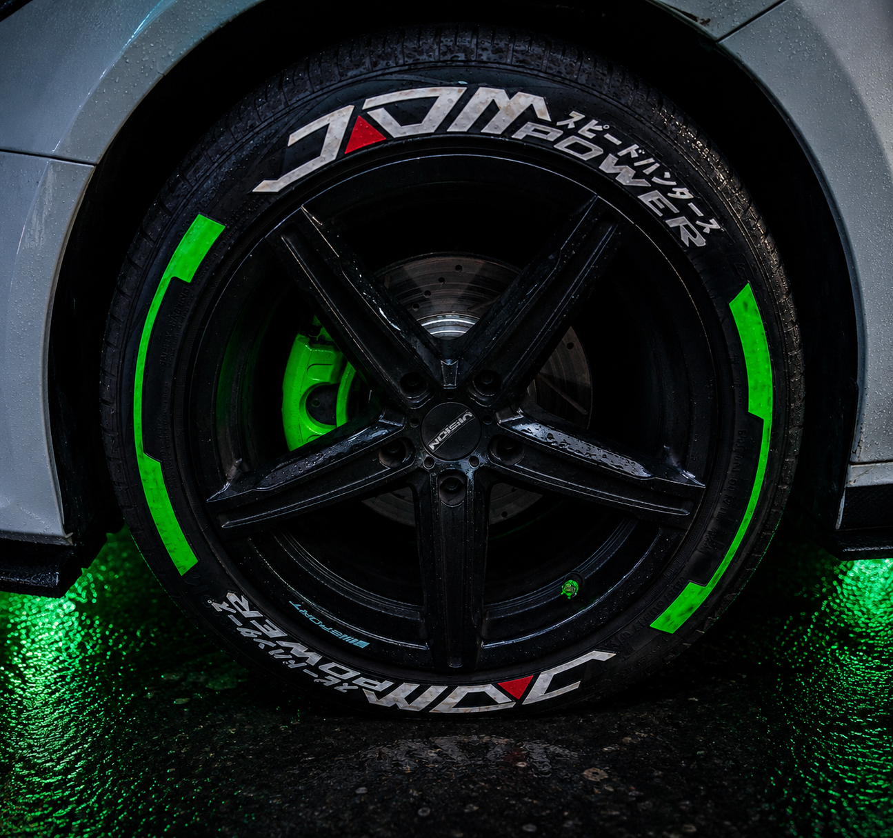 Rueda negra con letras verdes y blancas y caliper verde